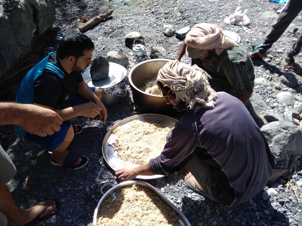 Un groupe d'hommes prépare la nourriture traditionnelle à base d'agneau et de riz à Oman, ils portent le chèche.