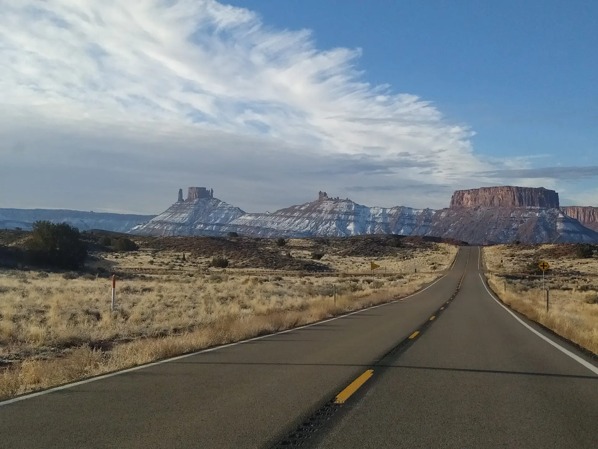 Route 128 in the desert of Moab Utah with snowy Castleton Tower and Parriott Mesa in the background.