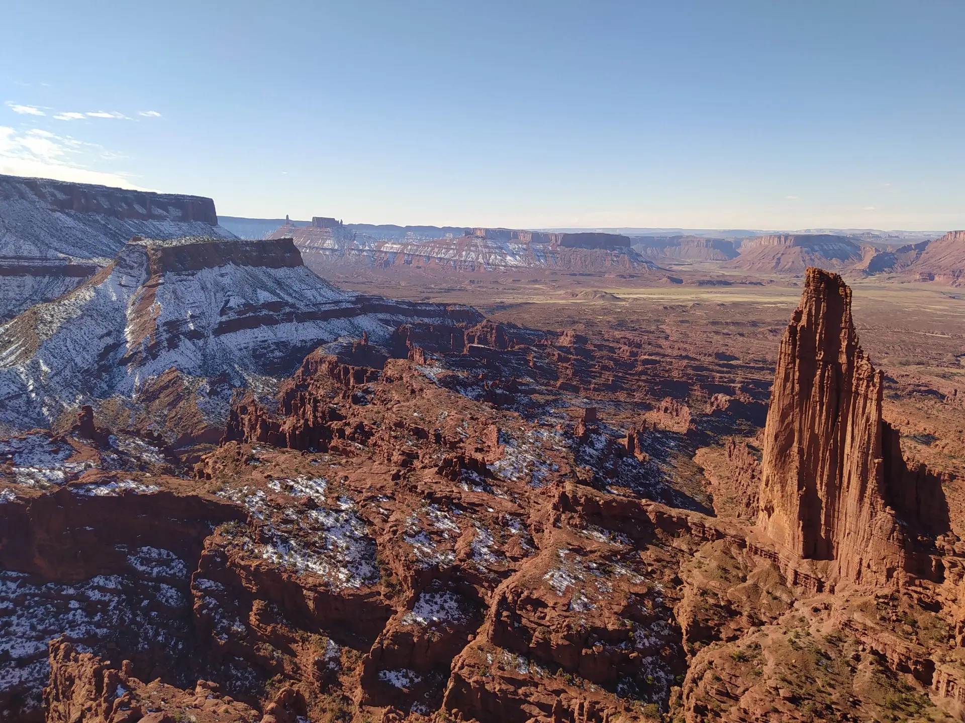 The amazing Titan Tower in the foreground of a desert landscape covered in snow in Utah.