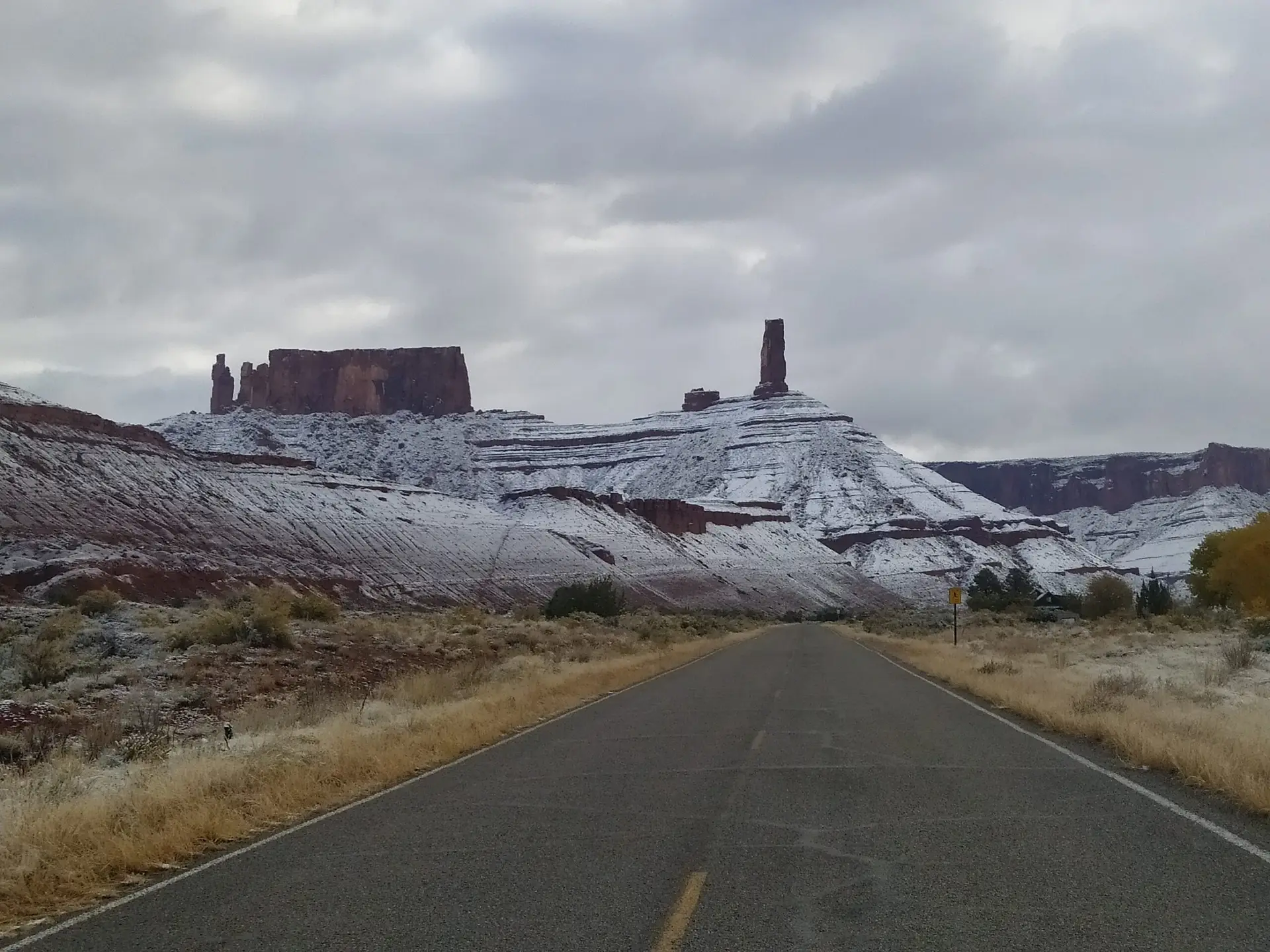 A the end of a road stands Castleton Tower in Castle Valley, Utah. The base of the cliff is covered in snow.